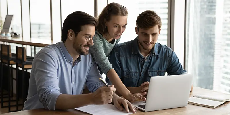 Personen arbeiten gemeinsam am Laptop und nutzen KI im Online Marketing